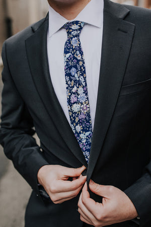 Lilac tie worn with a white shirt and dark gray suit.
