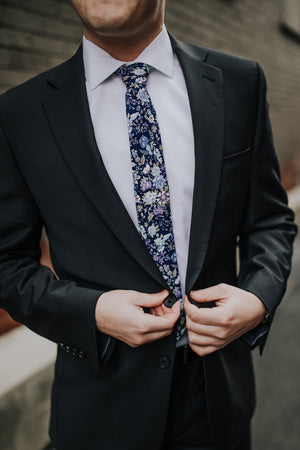 Lilac tie worn with a white shirt and dark gray suit.