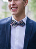 Lotus Bow Tie worn with a white shirt and navy suit jacket.
