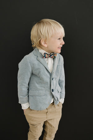 Mardi pre-tied bow tie worn by a young boy in a white shirt, gray blazer and tan pants. 