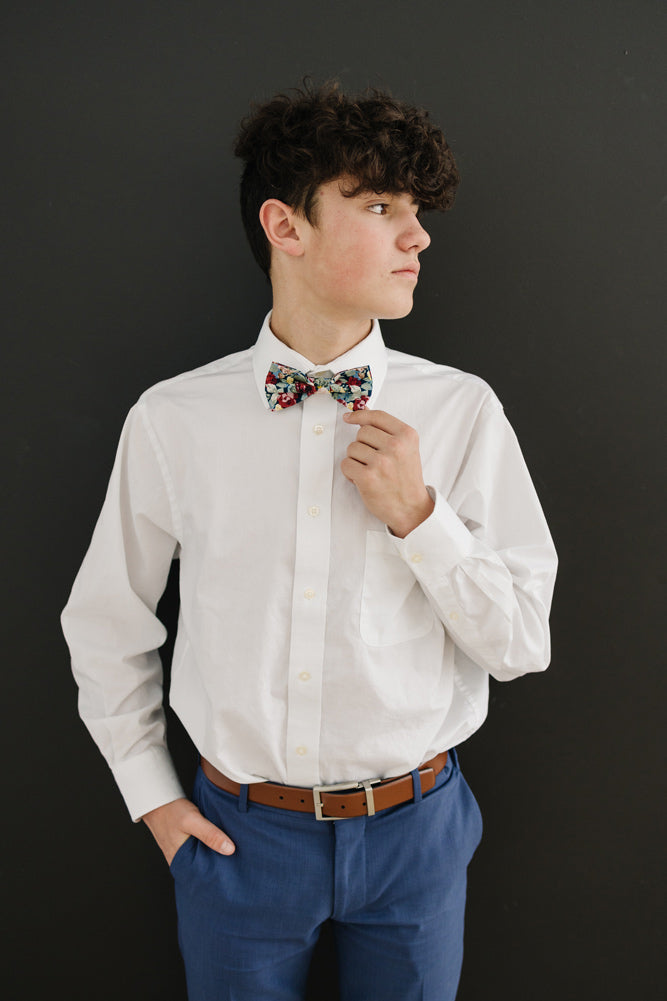 Mardi pre-tied bow tie worn with a white long sleeve shirt, brown belt and blue pants. 