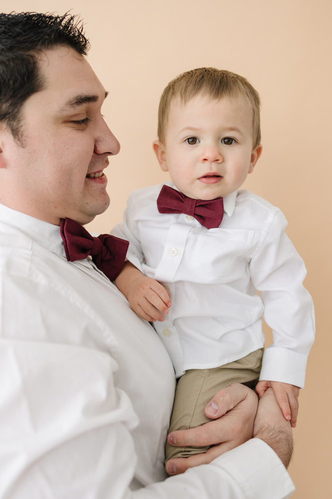 Merlot pre-tied bow ties worn by father and son in white long sleeve shirts. 
