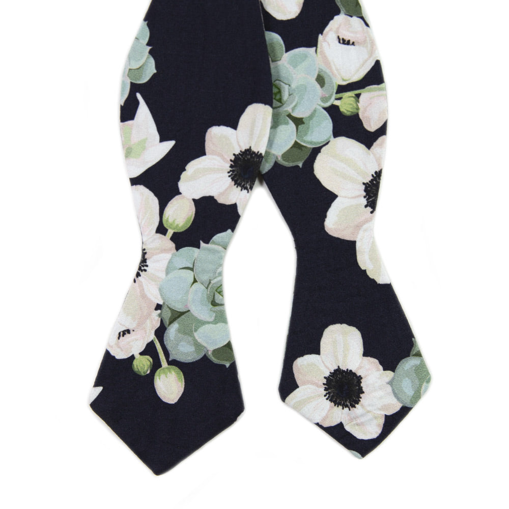 Mesa Self Tie Bow Tie. Navy background with big white flowers and sage green succulents.