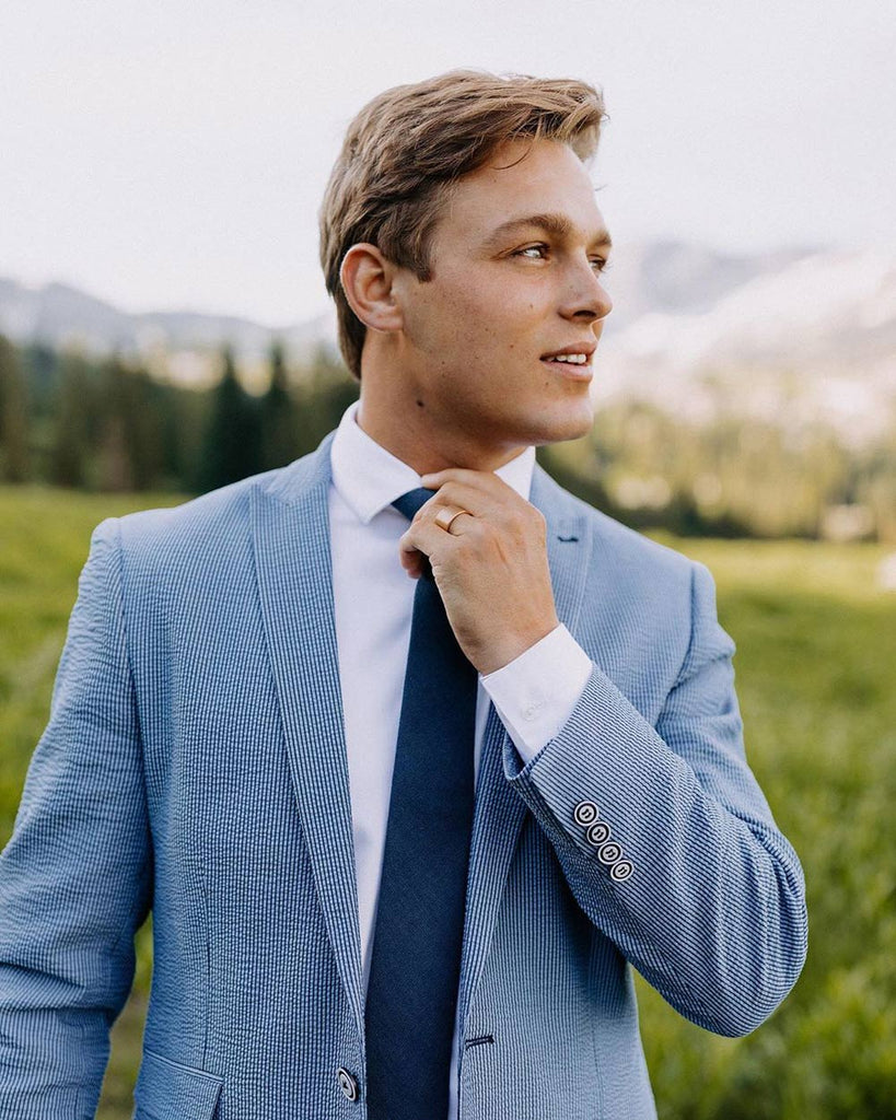 Navy tie worn with a white shirt and blue textured suit jacket.