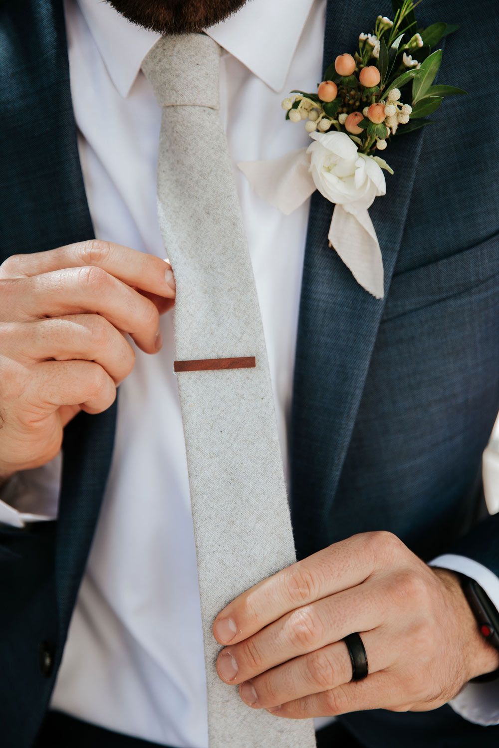 Onyx tie worn with a white shirt and blue suit and a wood tie clip.