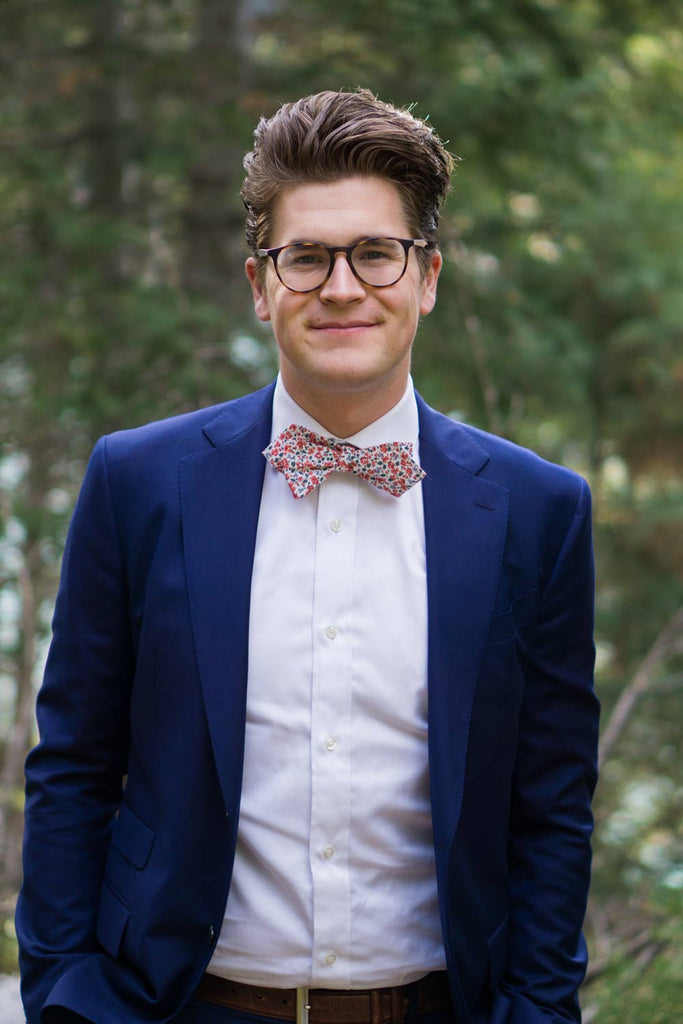 Peach Blossom Bow Tie worn with a white shirt and navy suit jacket.