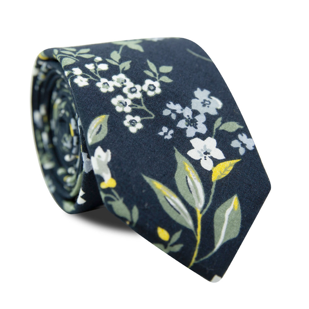 Rio Skinny Tie. Navy blue background with white and light blue flowers, green and yellow leaves and stems.