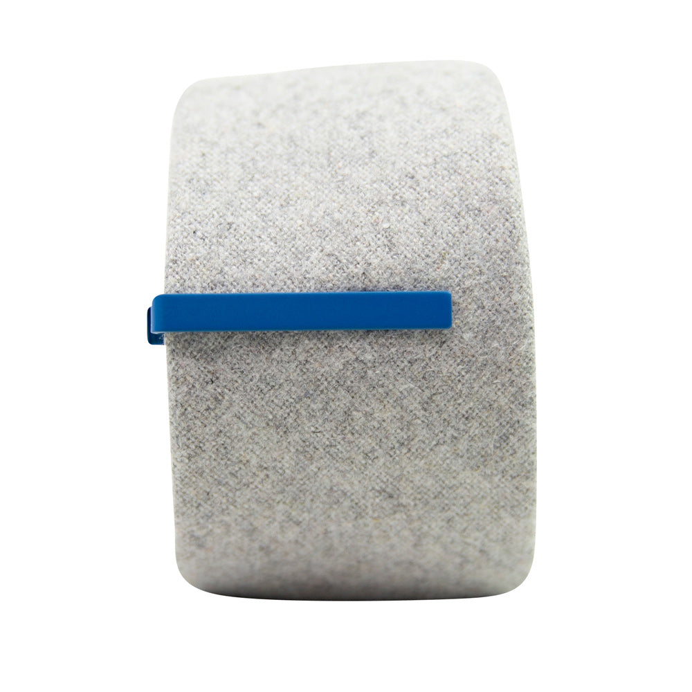 Solid royal blue metal tie bar clipped onto a gray textured wool tie that is rolled up.