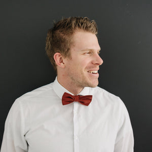 Rust pre-tied bow tie worn with a white long sleeve shirt.