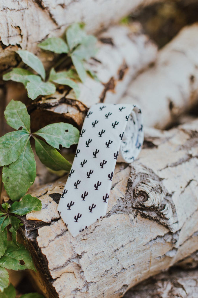 Saguaro tie sitting rolled up on a log next to green ivy.
