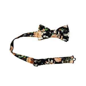 Secret Garden Pre-Tied Bow Tie with adjustable neck strap. Black background with light orange flowers, white and gray flowers, and green leaves.