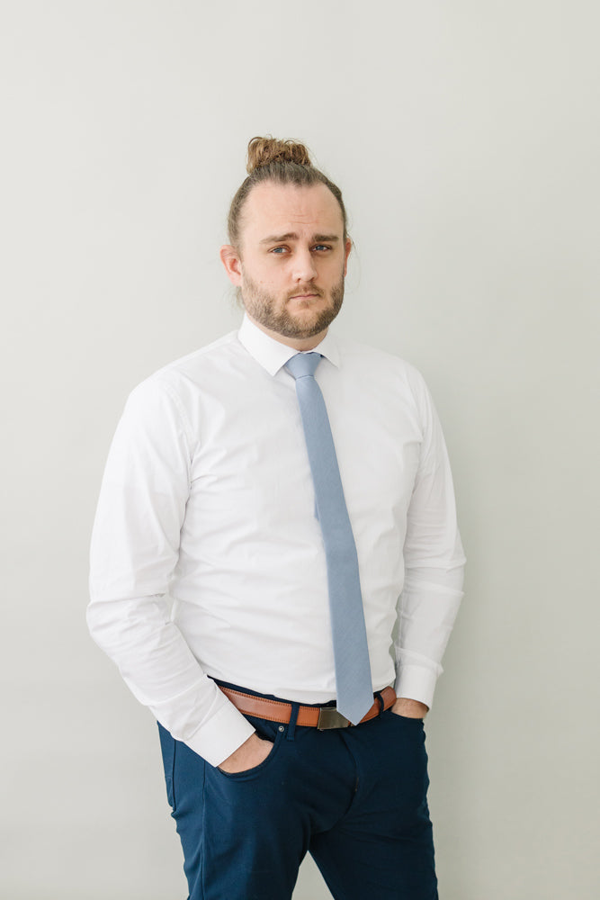 Steel tie worn with a white shirt, brown belt and navy pants.