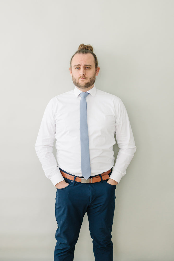 Steel tie worn with a white shirt, brown belt and navy pants.