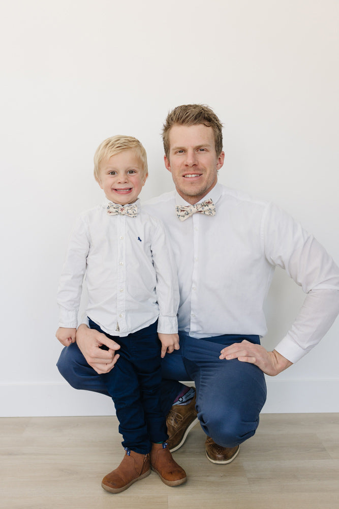 Sugar Blossom Pre-Tied Bow Ties worn by a dad and his son with white shirts and blue pants and brown shoes.