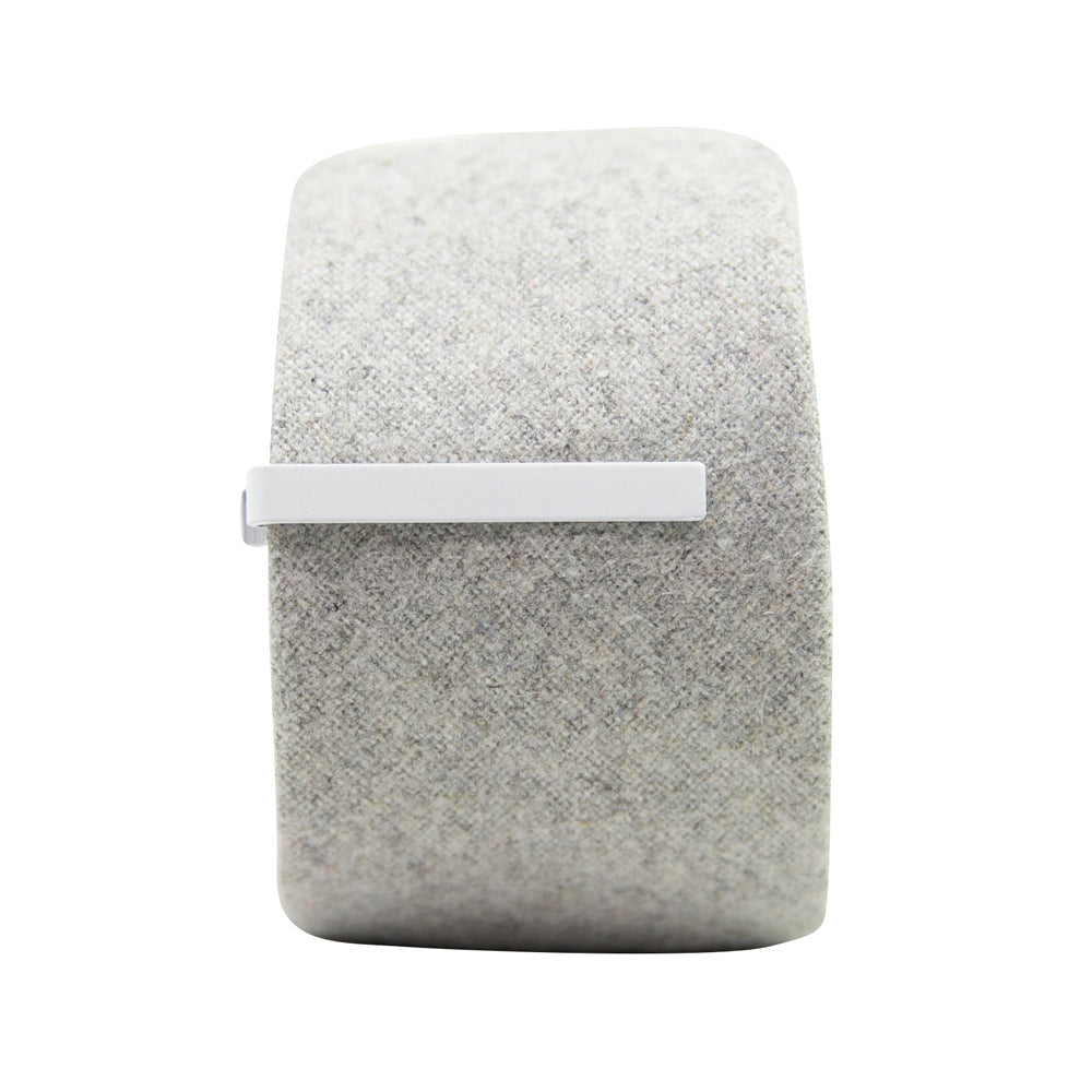 Solid white metal tie bar clipped onto a gray textured wool tie that is rolled up.